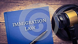 Immigration law book and gavel on a brown wooden table. Law and legal concept
