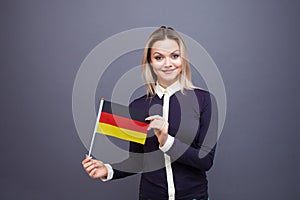 Immigration and the study of foreign languages, concept. A young smiling woman with a Germany flag in her hand.