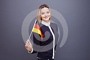 Immigration and the study of foreign languages, concept. A young smiling woman with a Germany flag in her hand.