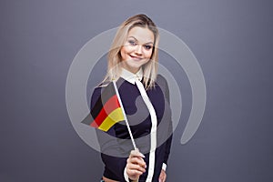 Immigration and the study of foreign languages, concept. A young smiling woman with a Germany flag in her hand.