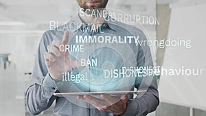 Immorality, behaviour, asocial, illegal, dishonest word cloud made as hologram used on tablet by bearded man, also used