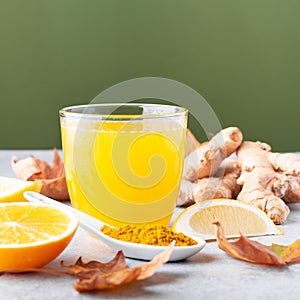 Immune boosting drink with citrus fruits, ginger, turmeric. Drink or smoothie with yellow fall leaves for autumn or virus season