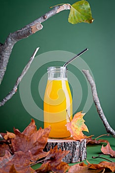 Immune system boosting drink or smoothie with ginger, citrus and turmeric on wooden stand for autumn or virus season on green