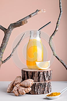 Immune system boosting drink or smoothie with ginger, lemon and turmeric on wooden stand for autumn or virus season on