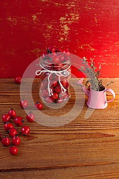 Immunity boosting treatments, infusions. Natural thyme, mint herbs and rosehip berries in a jar on a wooden background photo