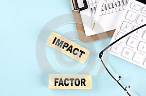IMPACT FACTOR text written on wooden block with clipboard,eye glasses and calculator Business concept