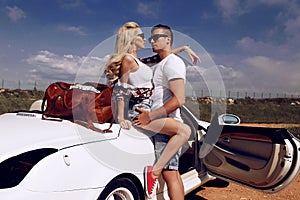 Impassioned couple in casual clothes, posing beside luxurious car