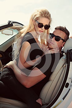 Impassioned couple in casual clothes, posing in luxurious car