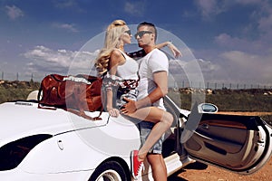 Impassioned couple in casual clothes, posing beside luxurious car photo