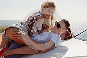 Impassioned couple in casual clothes, posing beside luxurious car photo