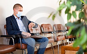 Impatient man in mask waiting at office