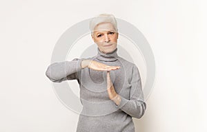 Impatient senior woman making time out gesture