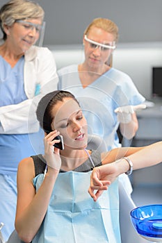 Impatient woman patient on phone at dental clinic