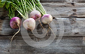 Imperfect sustainable turnips, green tops and roots on old wood