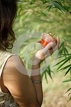 Impersonal brunette in the summer dress holding the red apple