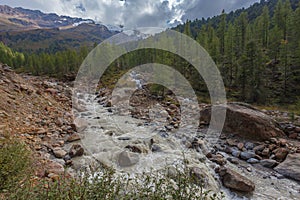 Impetuous muddy stream formed by the melting of the glacier in an alpine valley