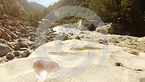 impetuous stream of river Ganges at it`s source among mountains Himalaya with green forest reflection of sun in small puddles