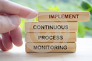 Implement Continuous Process Monitoring text on wooden blocks representing continuous Improvement Strategies