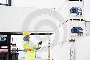 Import and Export concept. Foreman using laptop computer in the port of loading goods. Businessman with safety equipment working