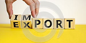 Import or export symbol. Hand is turning a cube and changes the word `import` to `export`. Beautiful yellow table, white