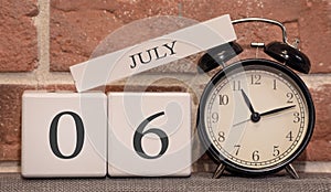 Important date, July 6, summer season. Calendar made of wood on a background of a brick wall. Retro alarm clock as a time