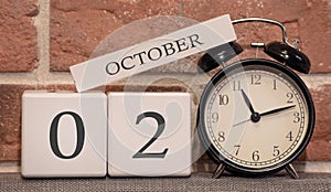 Important date, October 2, autumn season. Calendar made of wood on a background of a brick wall. Retro alarm clock as a time