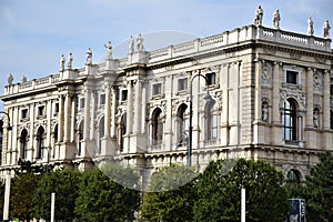 Imposing and historic palace, with columns on the facade and sides and many statues on the cornice, seen from the garden, in Vienn
