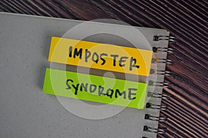 Imposter Syndrome write on sticky notes isolated on Wooden Table