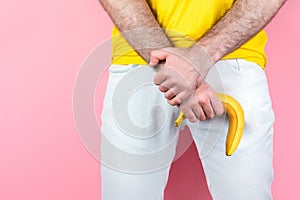 Impotencia pánska. muž v biely džínsy nohy oddelene krívanie banán najbližšie. ružový. z blízka 