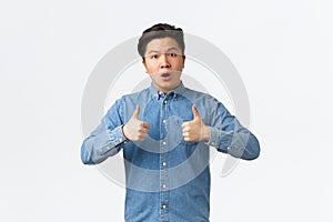 Impressed and astounded handsome asian guy showing thumbs-up and looking astonished at camera, congrats person with