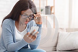 Impressed Black Girl In Eyeglasses Looking At Cellphone Screen With Disbelieve photo