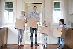 Impressed family carrying boxes moving in to new house