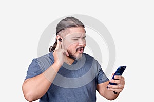 An impressed man listening to some sick tunes on his streaming app on his phone connected to bluetooth earphones. Isolated on a