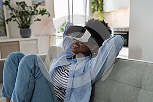 Impressions smiling African American young woman using VR headset immersing herself in metaverse