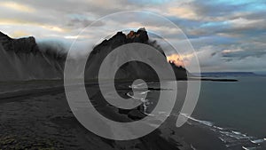 Impressive arial view of black sand beach in Iceland. Epic Vestrahorn mountains in cloudy weather. Calm, cold ocean