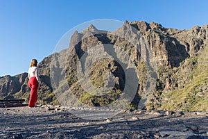 Impressive caucasian tourist in red pants in scenery hidden landscaped, stand with tranquility and relaxing. Harmony moody female