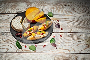 Impressive Cheese Plate or cheese platter snacks for Wine. Brushetta with mango, Camembert cheese and pomegranate served on a