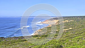 Impressive cliffs at Cape Espichel on coast of Atlantic Ocean in Portugal under blue sky.