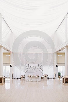Impressive large wedding hall with high white ceilings, bright parquet and decorated table for groom and bride
