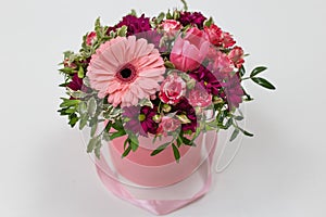 An impressive pairing composition of fresh flowers Rose, Gerbera, Tulip colors: beard, pink, green, white in a pink cardboard