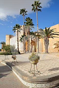 The impressive ramparts of the medina surrounded by colorful palmtrees and a large cobbled walkway in Sfax