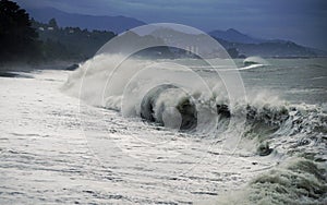 Impressive view of splashing storm with big waves hitting the sea coast in the evening. Background of Batumi, Georgia