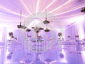 IMPRESSIVE VIOLET RECEPTION VENUE WITH BEAUTIFUL WHITE  WEDDING CAKE AT CANDY TABLES, FLORAL GREEN DECORATION, REFLECTIVE FLOOR, B