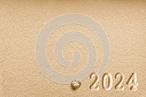 Imprints of numbers 2024 new year and a shell left side on a golden sand