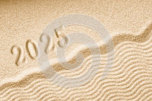 Imprints of numbers 2025 happy new year on a golden sand waves