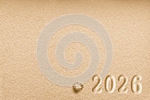 Imprints of numbers 2026 new year and a shell left side on a golden sand