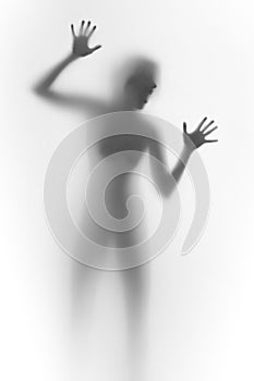 Imprisioned woman behind a glass wall, shouts. Face, silhouette, hands.