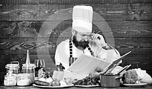 Improve cooking skill. Book recipes. According to recipe. Man bearded chef cooking food. Guy read book recipes. Culinary