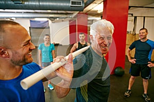 Improve shoulder stability with a pvc pipe. a senior man doing pvc pipe exercises with the assistance of his trainer.