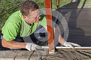 Improvement of the yard, a man evens out the concrete mortar with the rule